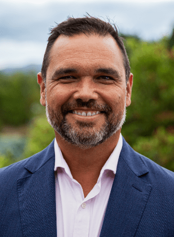 the image is of an Aboriginal man wearing a blue blazer and white shirt